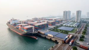 Comment intégrer les produits vietnamiens grâce à la logistique verte ? Port vietnamien moderne avec conteneurs colorés, navire cargo, voie ferrée électrifiée et équipements favorisant une logistique durable.