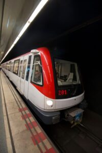Transport à Barcelone : quel réseau et quelle carte choisir ? Entrée d’une station de métro à Barcelone avec les panneaux de signalisation du réseau et des voyageurs sur le quai.