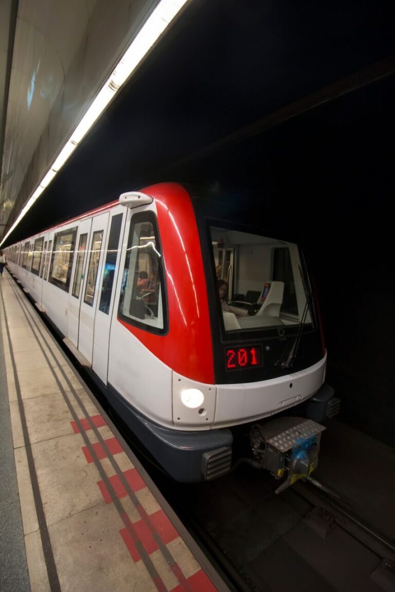 Entrée d’une station de métro à Barcelone avec les panneaux de signalisation du réseau et des voyageurs sur le quai.